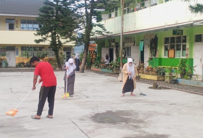 Guru dan pegawai salah satu sekolah di Kota Padangpanjang menyapu debu vulkanik Gunung Marapi di halaman sekolah.(Foto: Diskominfo Padangpanjang)